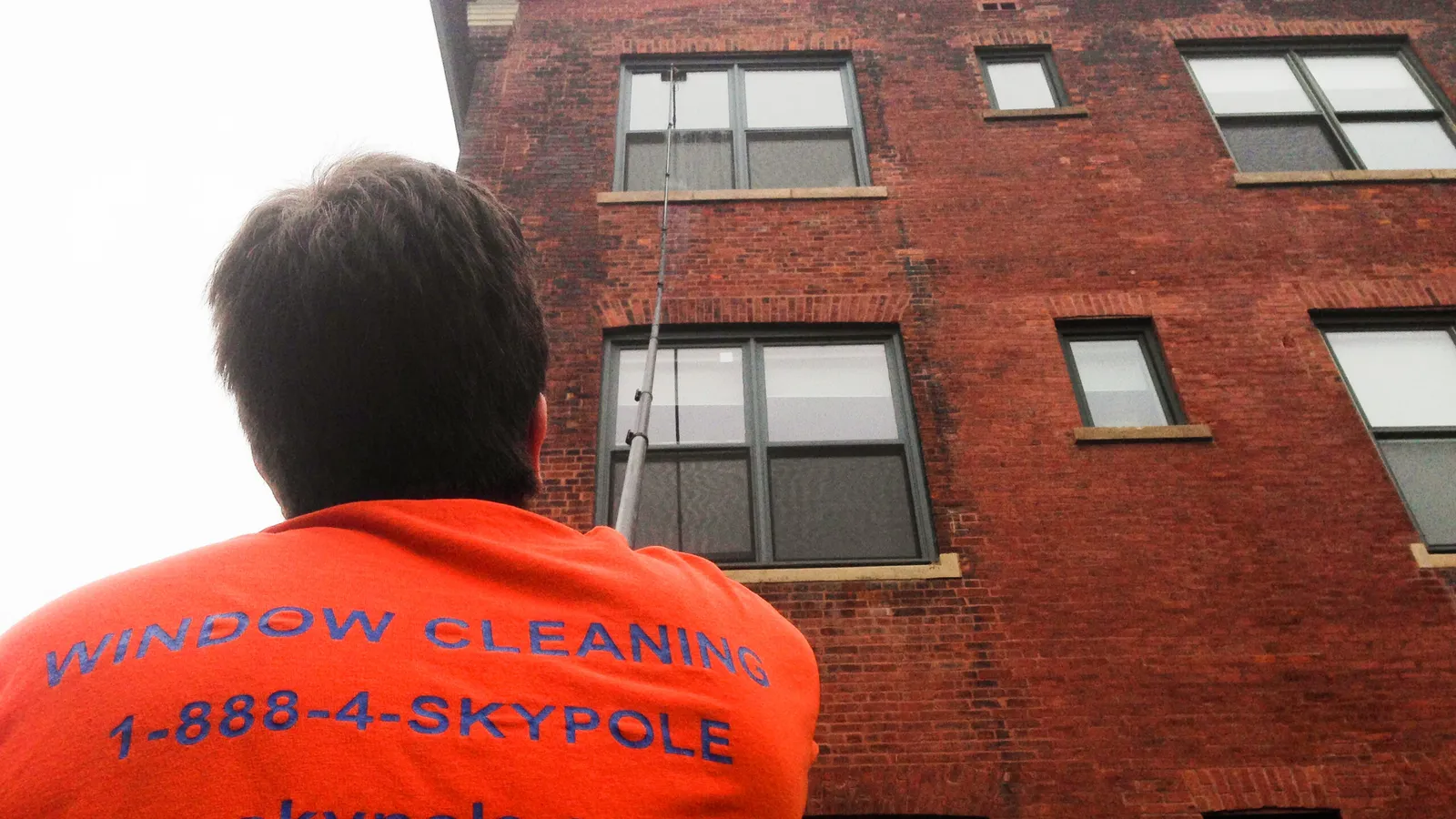 An employee of Skypole cleaning the windows of a building in Toronto