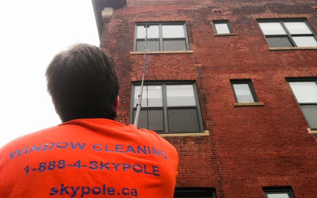 An employee of Skypole cleaning the windows of a building in Toronto