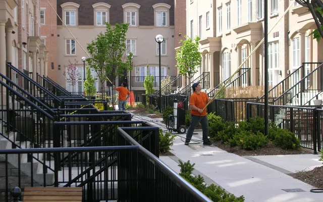Workers cleaning pathway in urban residential area