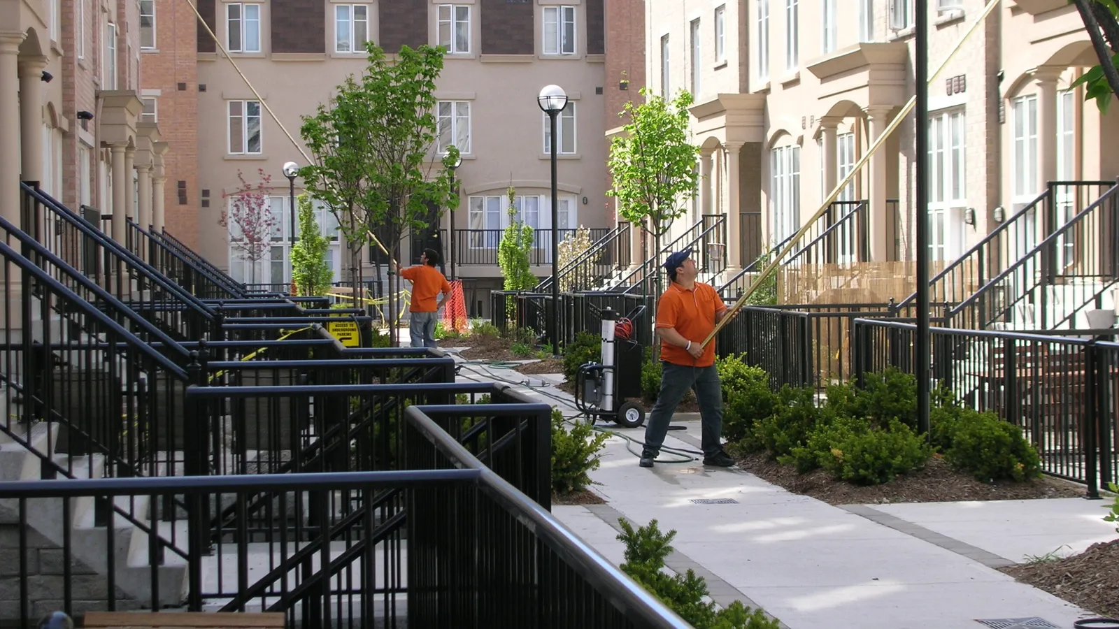 Workers cleaning pathway in urban residential area