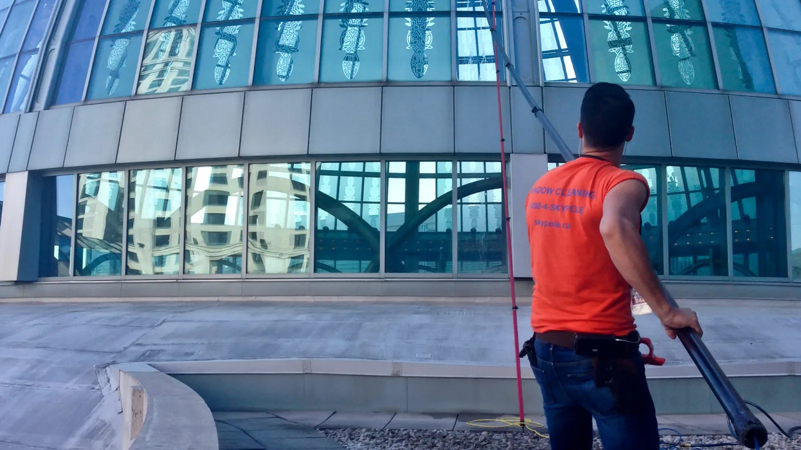 Worker cleaning glass dome building with pressure washer
