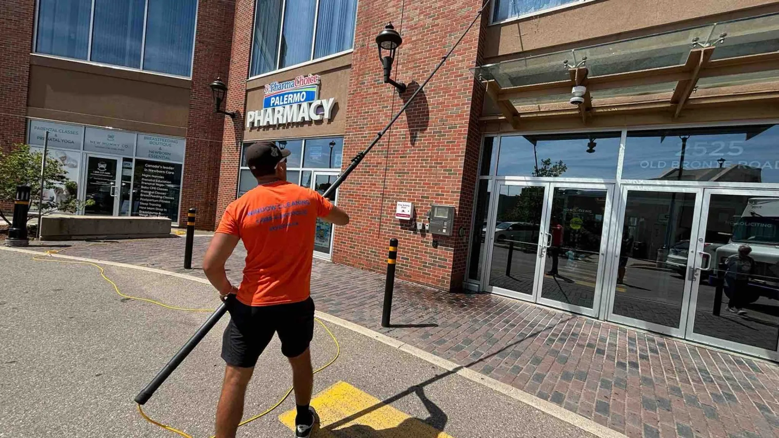 SKYPOLE technician using a water-fed pole to clean exterior windows at 2525 Old Bronte Road in Oakville