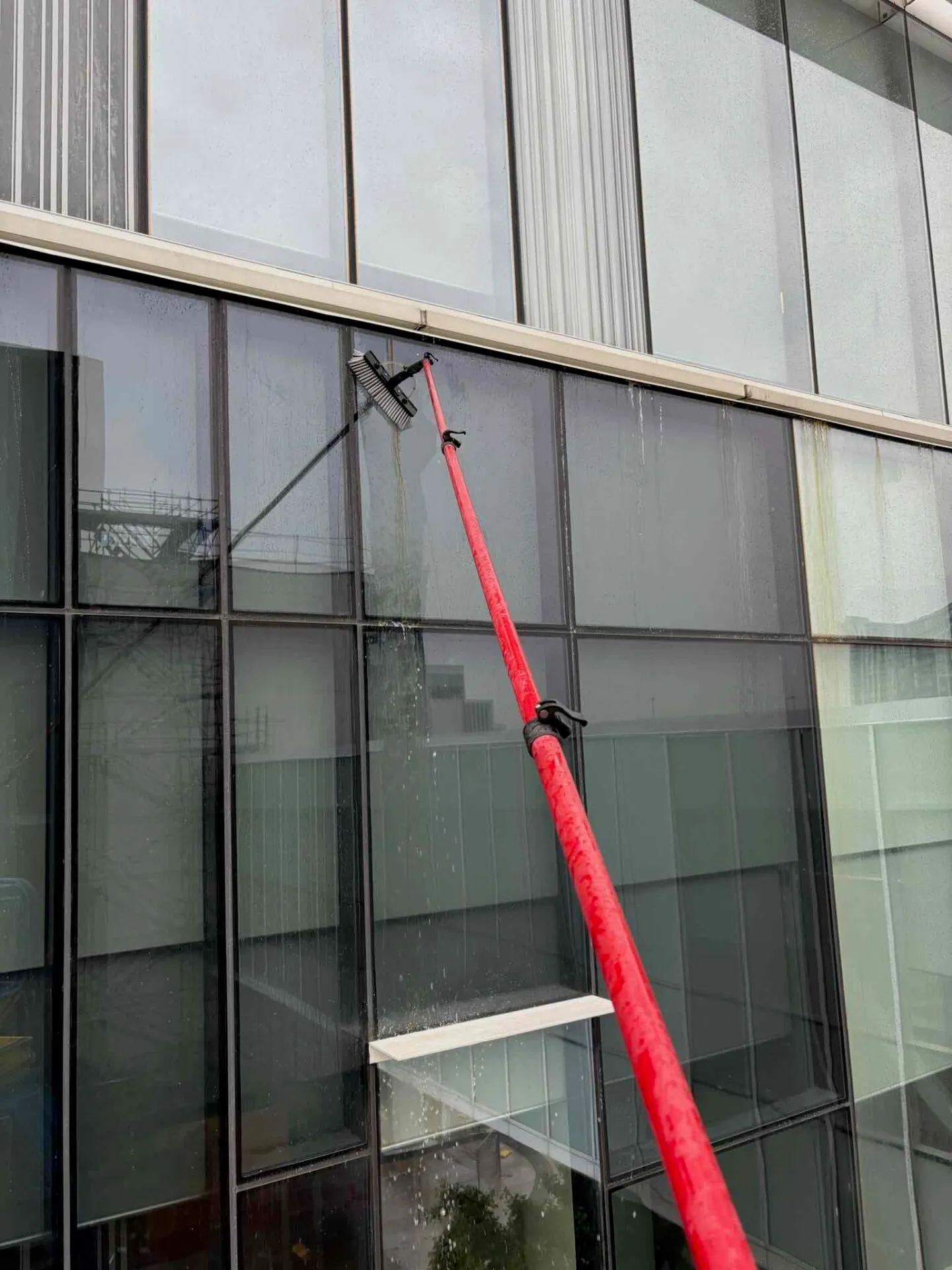 Red water-fed pole cleaning office building windows
