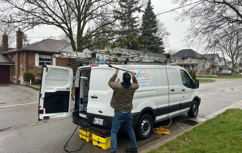 Man loading equipment onto roof of van in driveway.