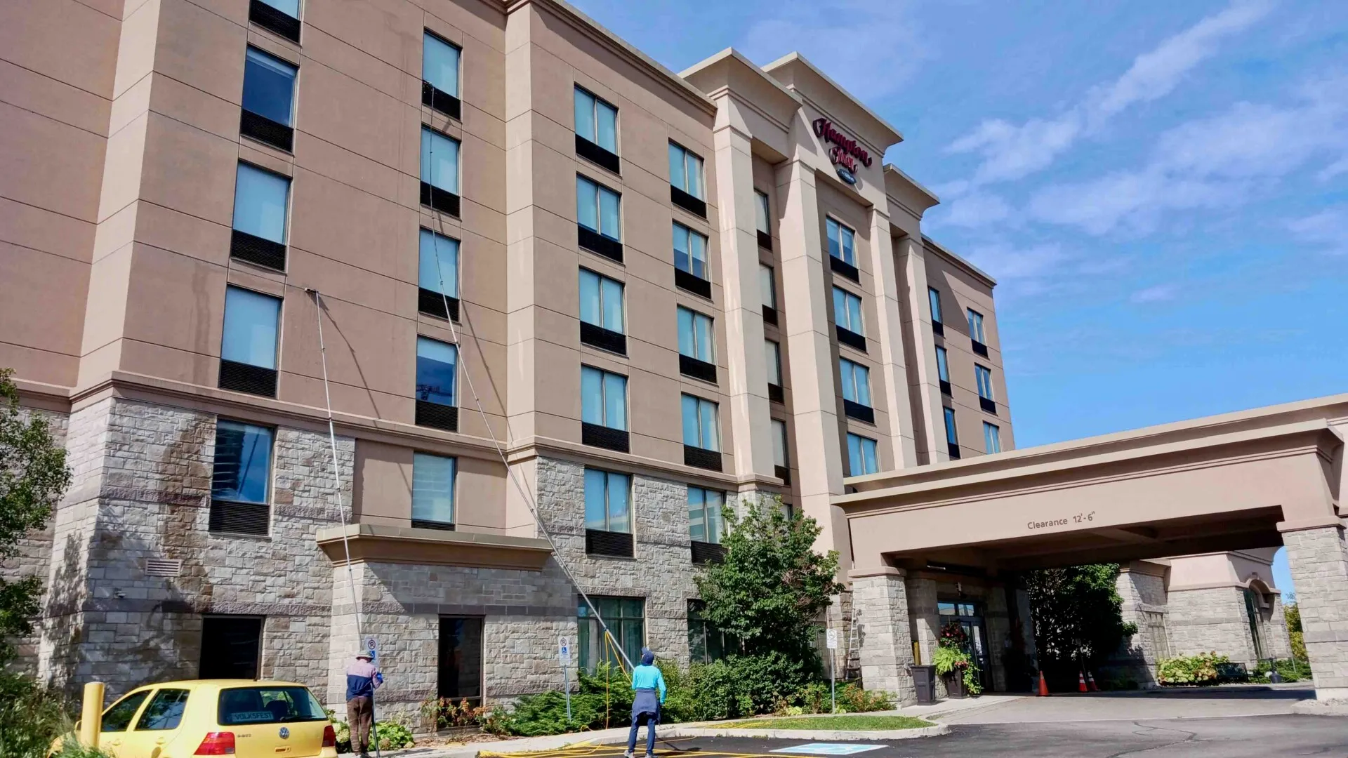 Hampton Inn hotel exterior with workers cleaning the windows and blue sky