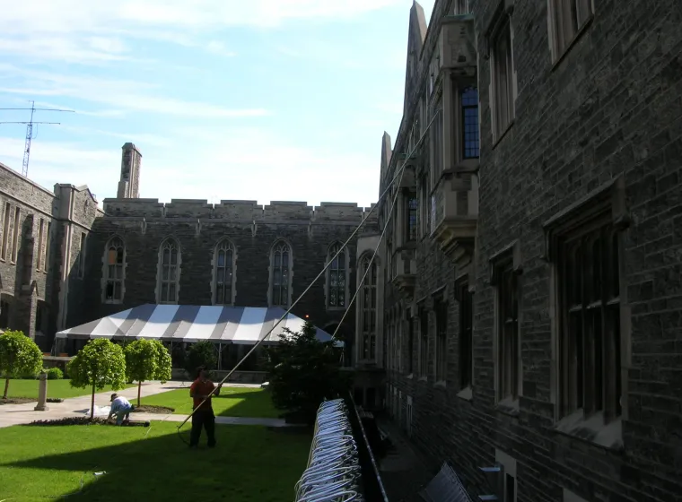 Historic university building with workers in courtyard.