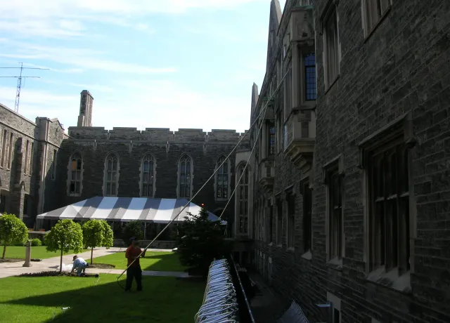 Historic university building with workers in courtyard.