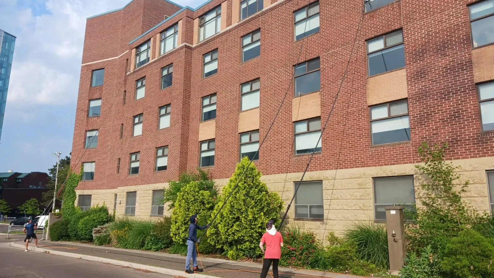 Skypole technicians using water-fed poles to clean exterior windows at Hedden Hall, McMaster University in Hamilton.