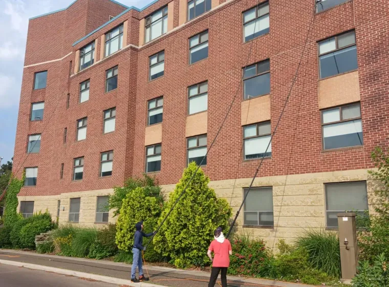 Skypole technicians using water-fed poles to clean exterior windows at Hedden Hall, McMaster University in Hamilton.