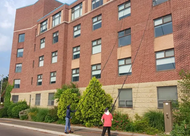 Skypole technicians using water-fed poles to clean exterior windows at Hedden Hall, McMaster University in Hamilton.