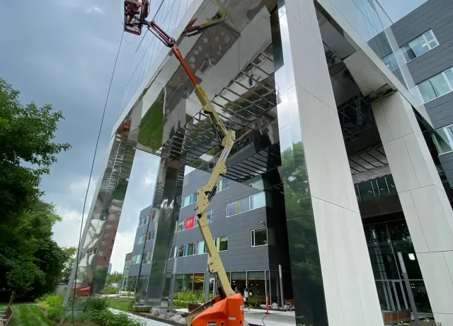 Cherry picker crane at modern glass building.
