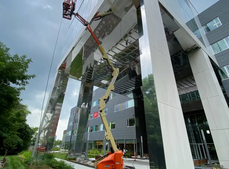 Cherry picker crane at modern glass building.