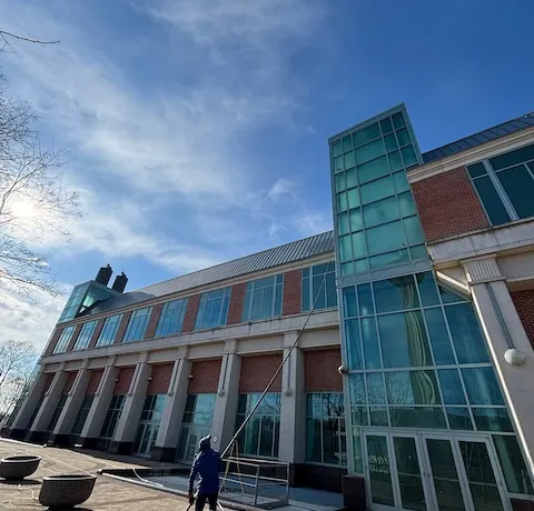 Person cleaning the windows of a modern glass-fronted building