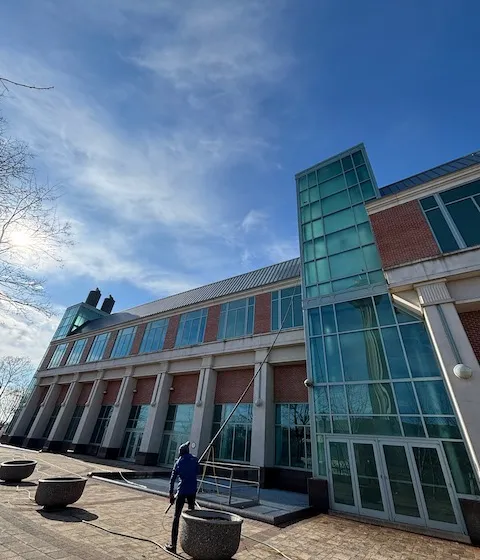 Person cleaning the windows of a modern glass-fronted building