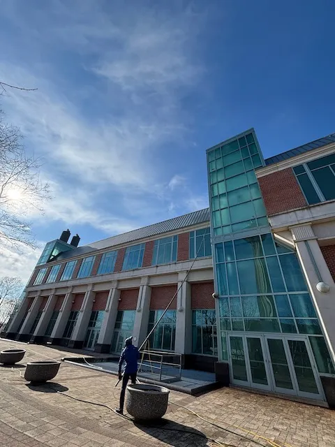 Person cleaning the windows of a modern glass-fronted building