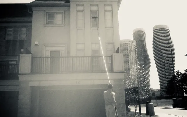 Man washing windows, townhouse, tall curved buildings background