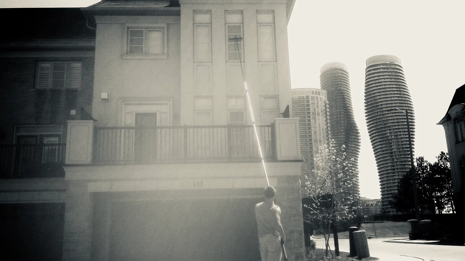 Man washing windows, townhouse, tall curved buildings background