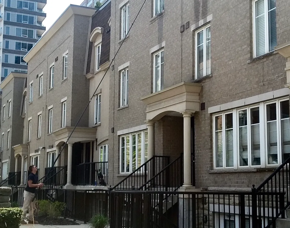 Man power washing modern townhouse exterior