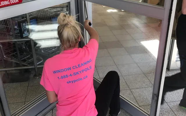 Worker in pink shirt cleaning automatic sliding door