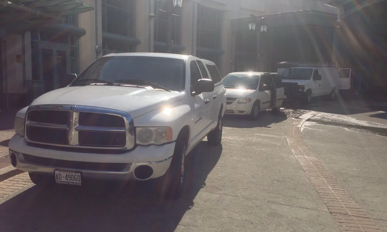 Sunlit parking area with several white vehicles