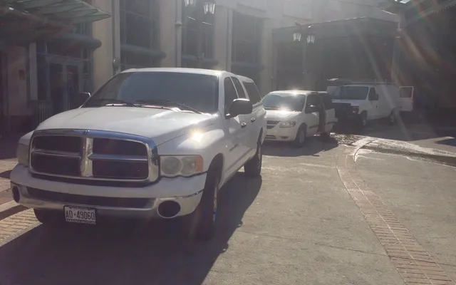 Sunlit parking area with several white vehicles