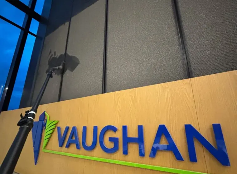 Commercial high dusting services inside Vaughan City Hall atrium cleaning elevated black architectural panels above lobby signage.