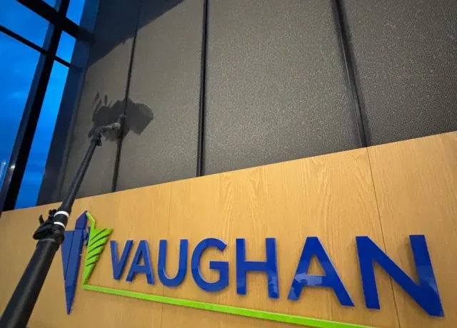 Commercial high dusting services inside Vaughan City Hall atrium cleaning elevated black architectural panels above lobby signage.