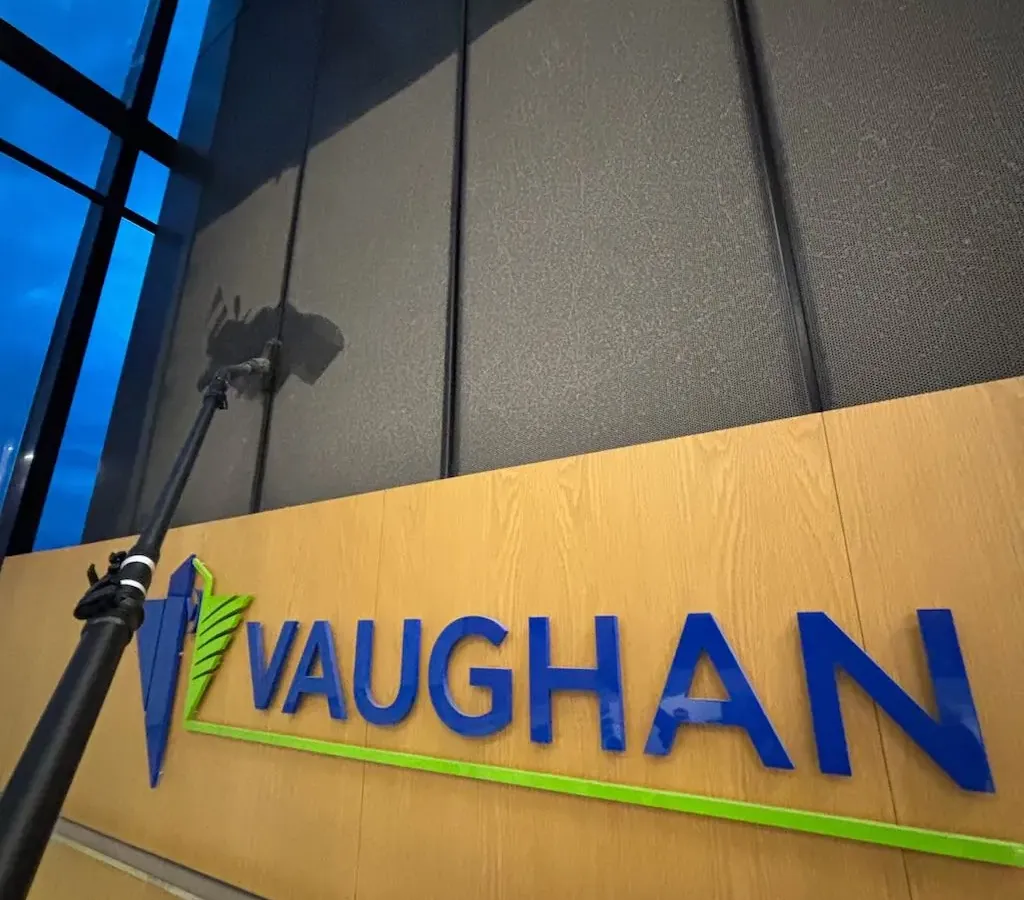 Commercial high dusting services inside Vaughan City Hall atrium cleaning elevated black architectural panels above lobby signage.