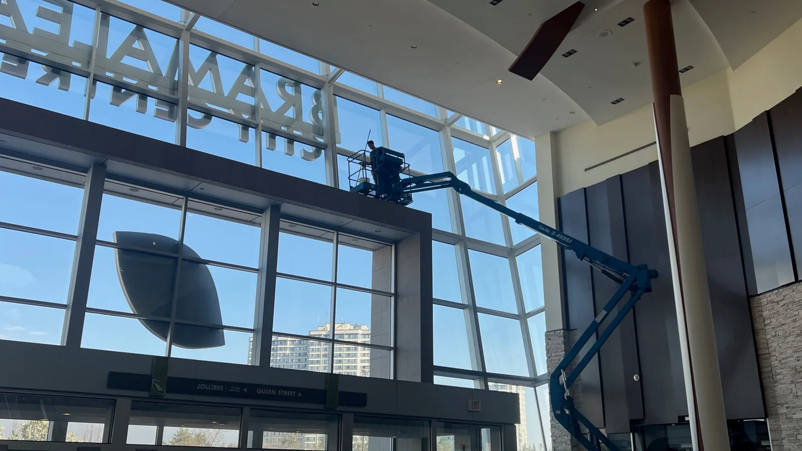 Worker on lift inside spacious modern lobby.