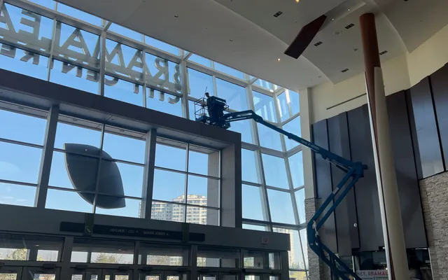 Worker on lift inside spacious modern lobby.
