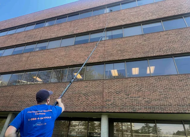 Window cleaner using telescopic pole at office building.