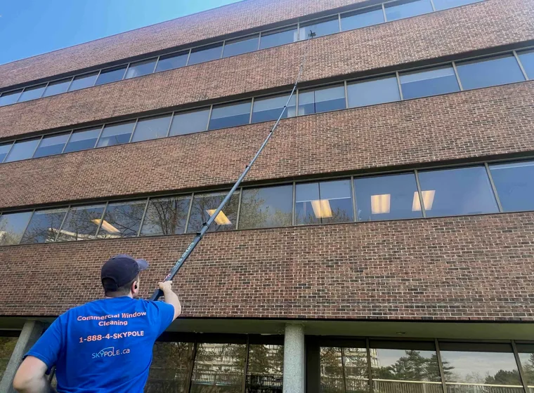 Window cleaner using telescopic pole at office building.