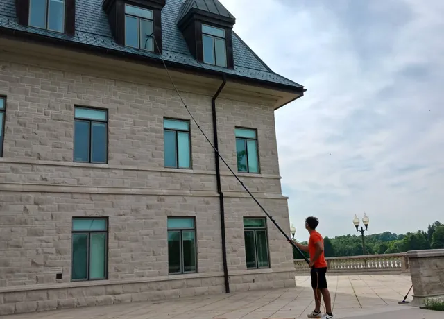 Man cleaning windows of large stone building
