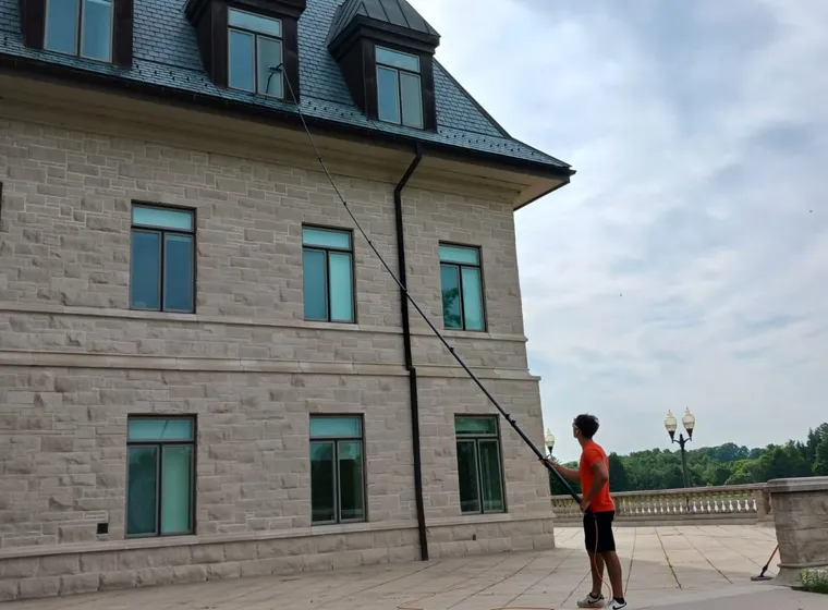 Man cleaning windows of large stone building