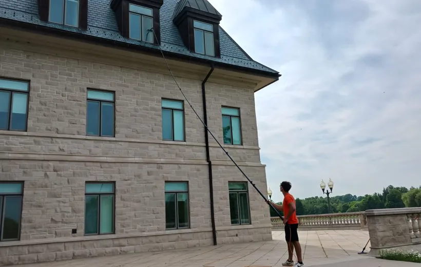 Man cleaning windows of large stone building