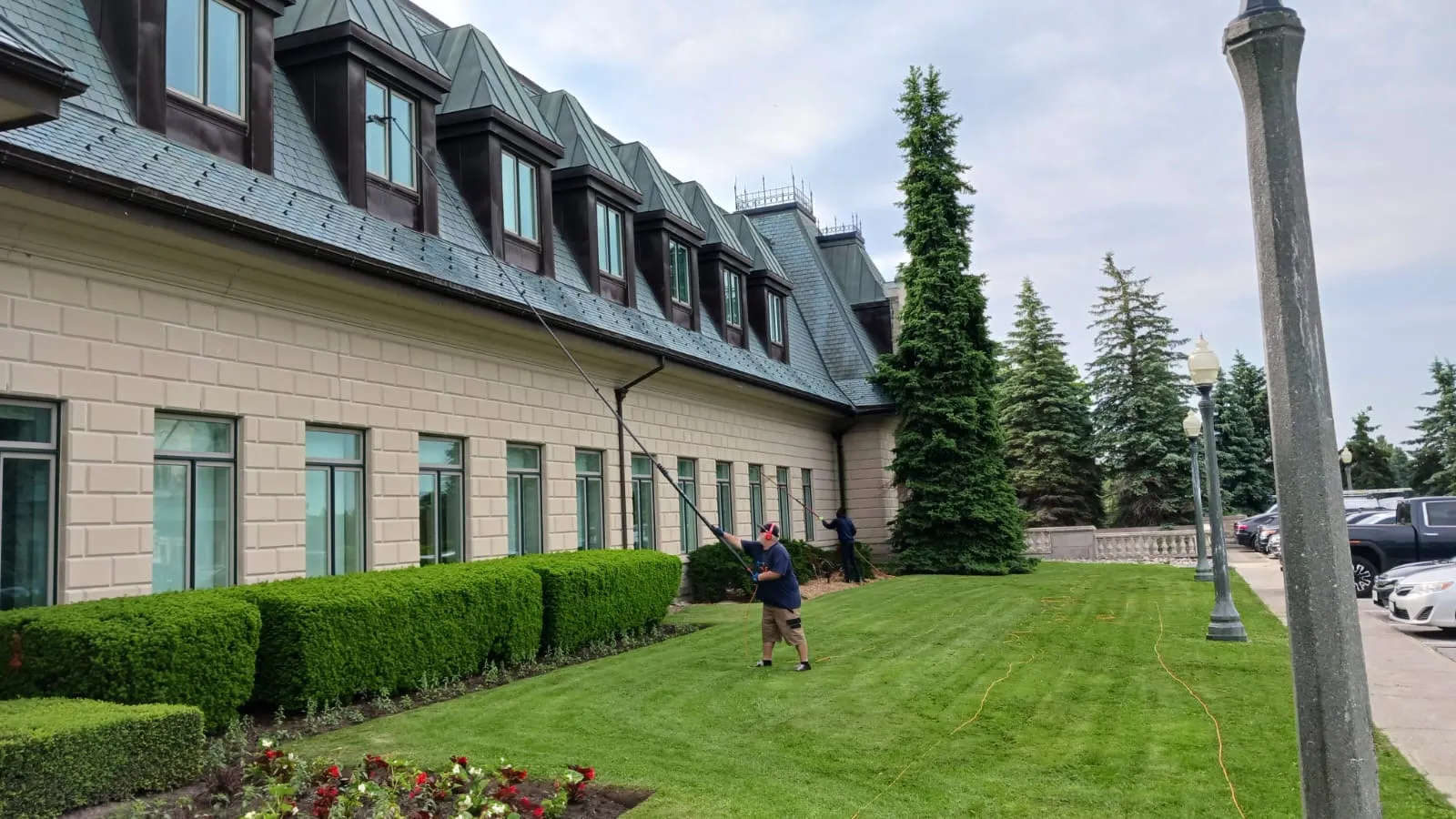 Man power washing lawn near large house