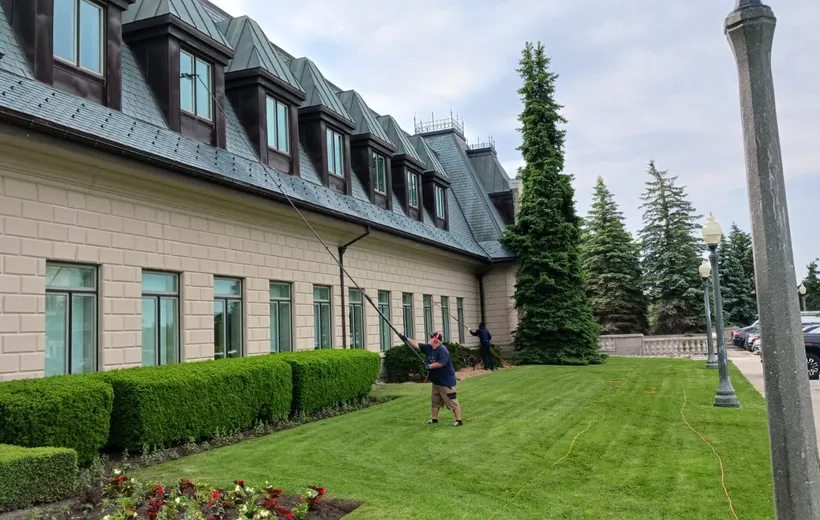 Man power washing lawn near large house