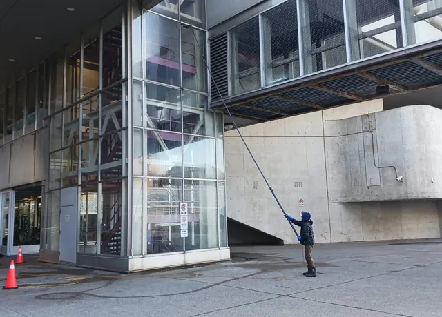 Person cleaning windows on modern building facade