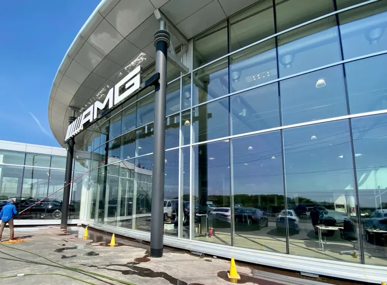 AMG dealership exterior with worker washing windows.