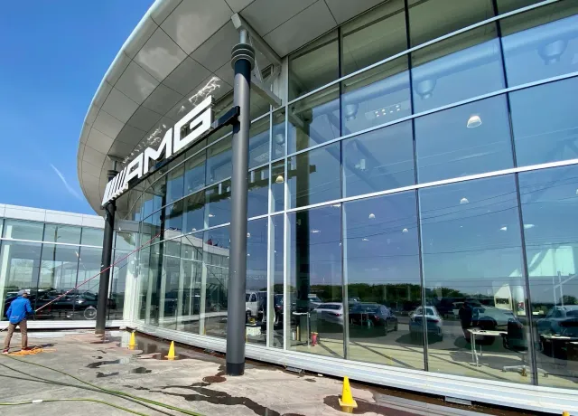 AMG dealership exterior with worker washing windows.