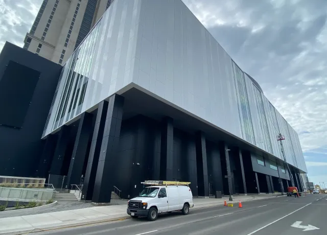 Modern urban building facade with van parked outside.