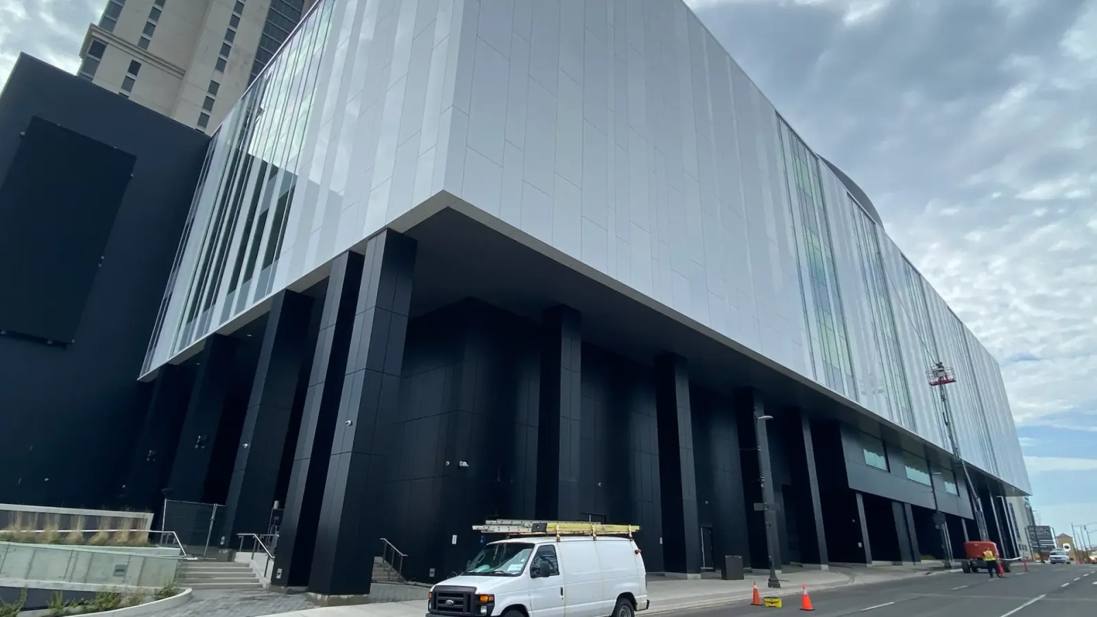 Modern urban building facade with van parked outside.