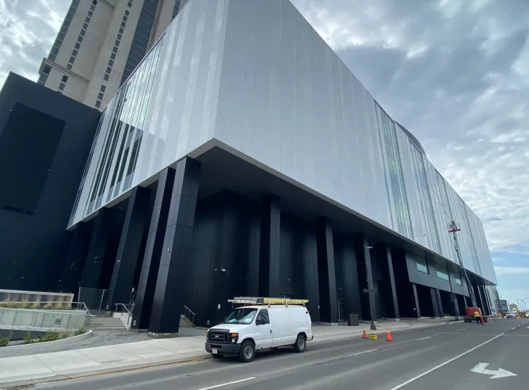 Modern urban building facade with van parked outside.
