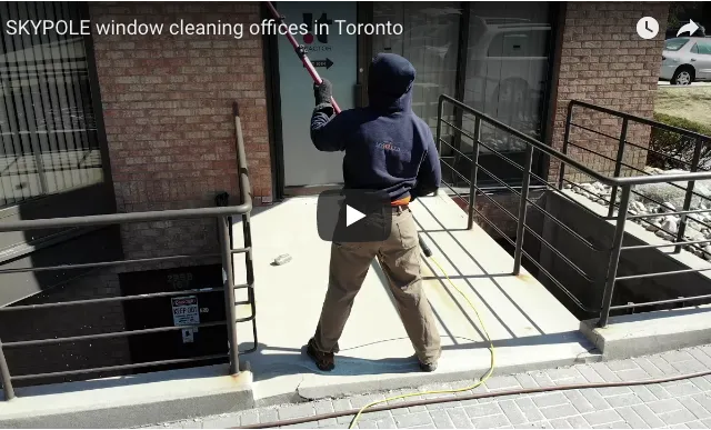 Worker cleaning office windows in Toronto with water-fed pole