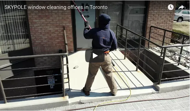 Worker cleaning office windows in Toronto with water-fed pole