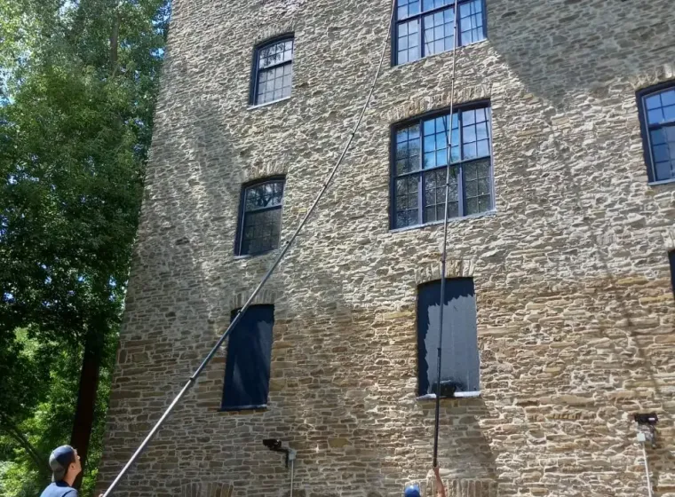 Two men cleaning windows of a large stone building.