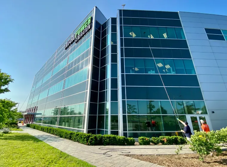 Modern office building with landscaped garden and workers outside.