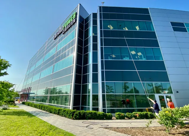 Modern office building with landscaped garden and workers outside.