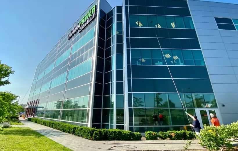Modern office building with landscaped garden and workers outside.