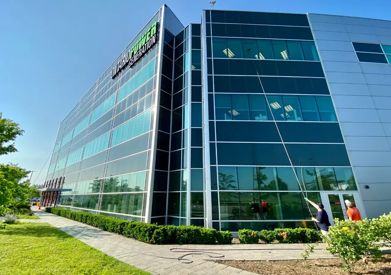 Modern office building with landscaped garden and workers outside.